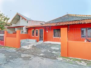ein rotes Haus mit einem orangenen Zaun davor in der Unterkunft SPOT ON 92539 Luqman Kostel Syariah in Semarang