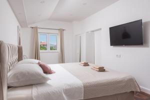 a white bedroom with a bed and a flat screen tv at Apartman Anastazije Deluxe in Solin