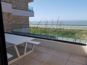 eine Bank auf einem Balkon mit Blick auf den Strand in der Unterkunft The One - New luxury beachfront apartment in Blankenberge
