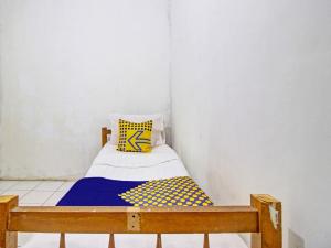 ein kleines Bett mit einem gelben und blauen Kissen darauf in der Unterkunft SPOT ON 92539 Luqman Kostel Syariah in Semarang