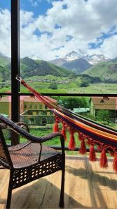 a hammock on a balcony with a view of mountains at North Kazbegi in Stepantsminda