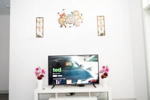 un televisor sentado en un puesto blanco con flores en Regal Apt with King & Queen Bed for Long-Term Stay, en Whitestown