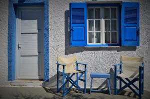 two blue chairs sitting outside of a building with a window at Summer Residence in Provatas