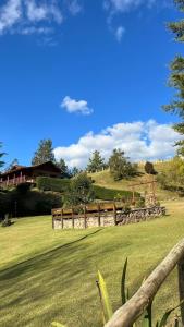 a wooden fence in a field with a house at Pousada Som das Aguas in Gonçalves