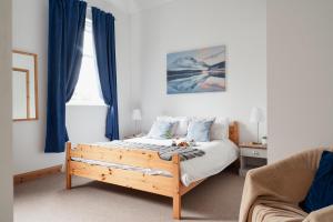 a bedroom with a bed with blue curtains and a couch at The Post House - Seasgair Lodges in Kingussie