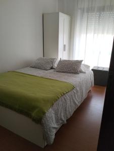 1 dormitorio con 1 cama con manta verde y ventana en Apartamento T2, en Vila Praia de Âncora