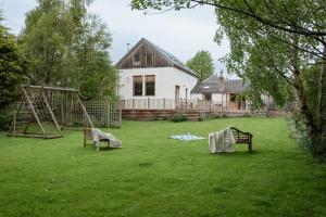 a yard with a swing set and a house at The Post House - Seasgair Lodges in Kingussie
