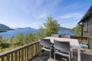 una mesa y sillas en una terraza con vistas al agua en Cozy and unassuming cabin with fantastic views, en Ørnes