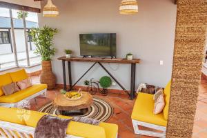 sala de estar con muebles de color amarillo y TV en Raizes AXM I Casa Campestre I Armenia, Quindío, Colombia, en Armenia