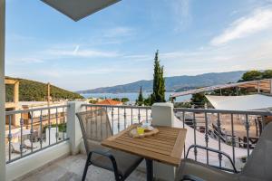 balcón con mesa de madera, sillas y vistas. en Evita's Resort en Poros