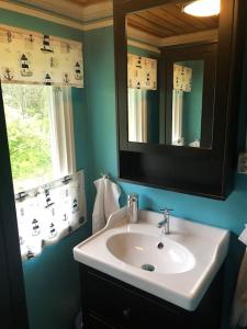 baño con lavabo, espejo y ventana en Cottage with own beach, seaterrace & pavillion. en Mariehamn