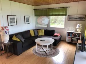 ein Wohnzimmer mit einem schwarzen Sofa und einem Tisch in der Unterkunft Cottage with own beach, seaterrace & pavillion. in Mariehamn