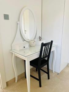 a white dressing table with a mirror and a black chair at Highland Forest Zimmers in El-Rom +18 photos