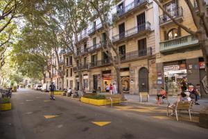 a city street with people sitting on chairs in front of a building at 41COB1019- Charming rustic apartment in Barcelona