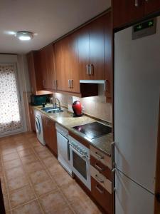 - une cuisine avec des placards en bois et un réfrigérateur blanc dans l'établissement El Nido de Candeleda, à Candeleda