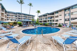 a swimming pool with lounge chairs and a resort at Kona Reef Comfort D6 in Kailua-Kona
