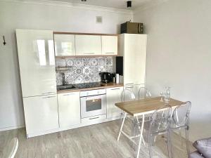cocina con armarios blancos, mesa y sillas en Apartment Chambre Nowolipki, en Varsovia
