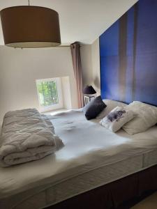 um quarto com uma grande cama branca com almofadas em La PULCINELLA Maison de Famille em Pouzilhac