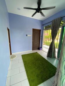 a living room with a ceiling fan and a green rug at HOMESTAY JERAI GEOPARK in Guar Chempedak