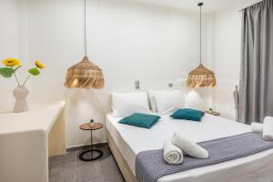 a white bedroom with a white bed with blue pillows at Jonathan City Apartment in Kos Town