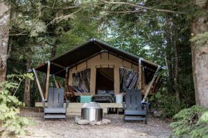 une tente dans les bois avec deux chaises et une table dans l'établissement Lumen Nature Retreat, à Woodstock