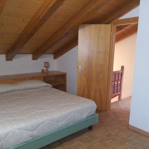 een slaapkamer met een bed en een houten deur bij Col Rodella in Campitello di Fassa