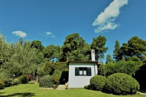 a small white chapel in a park with trees at Villa Pigadi Nikiti beach vacation in Metamorfosi