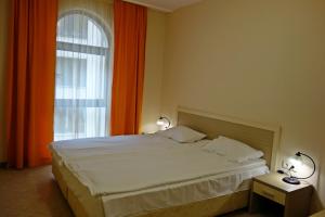 サニービーチにあるApartment 32 Royal Sunのベッドルーム1室(ベッド1台付)、窓(オレンジ色のカーテン付)