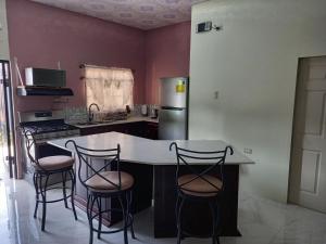 une cuisine avec un comptoir et quatre tabourets de bar dans l'établissement kdk villa, à Buccoo
