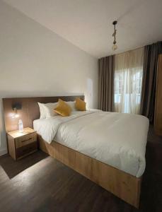 1 dormitorio con 1 cama grande con sábanas blancas y almohadas amarillas en Beach breeze, en Essaouira
