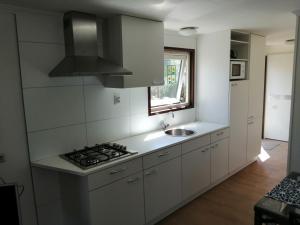 a kitchen with white cabinets and a sink and a stove at Recreatiepark Maas en Bos in Wellerlooi
