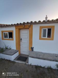 a white house with a door and two windows at Cute Yellow house at the beach in Praia da Arrifana