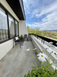 uma varanda com duas cadeiras e algumas flores em Matkráin Apartments em Hveragerði