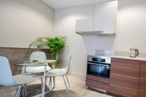 a kitchen with a glass table and white chairs at Newly build Utopia The Den Apartment 7-Minutes From Rotterdam City app2 in Schiedam