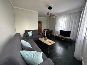 a living room with a couch and a tv at Agnanti Apartment in Kavála
