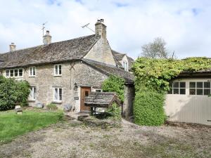 an old stone house with a bench in front of it at Friesland Cottage in Shilton