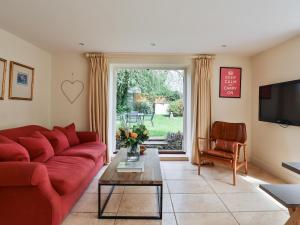 a living room with a red couch and a table at Friesland Cottage in Shilton