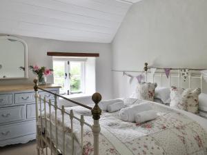 a white bedroom with a bed and a dresser at Friesland Cottage in Shilton