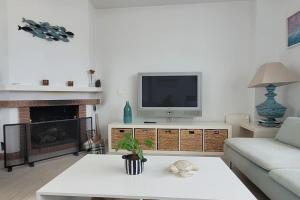 ein Wohnzimmer mit einem TV, einem Sofa und einem Kamin in der Unterkunft ATICO con vistas al mar a 100 metros de la playa in Torre de Benagalbón