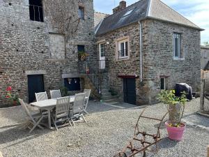 una mesa y sillas frente a un edificio en Domaine de la Ville Chérel, maison en pierre, en Pontorson