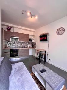 sala de estar con sofá y reloj en la pared en Logesty Home proche Paris et Metro, en Pantin