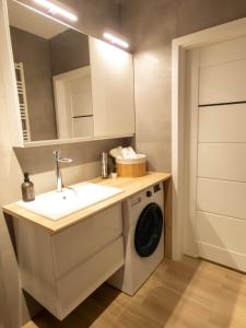 a bathroom with a washing machine under a sink at Apartament Flat 33 Suwałki in Suwałki