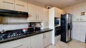 a kitchen with white cabinets and a black refrigerator at La Villa de Norma in Guayaquil