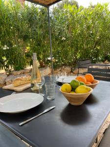 Home Cassis - Maison Les Calanques - Piscine chauffée في كاسيس: طاولة مع وعاء من الفواكه وزجاجة من النبيذ