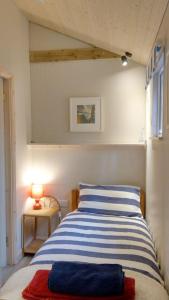 a bedroom with a blue and white striped bed at Secluded cosy cabin near town centre in St Austell