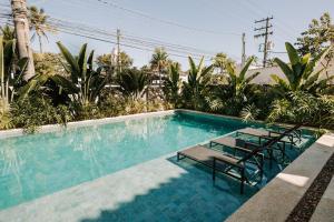 a swimming pool with two chairs and a table at Pousada Zama in Camburi