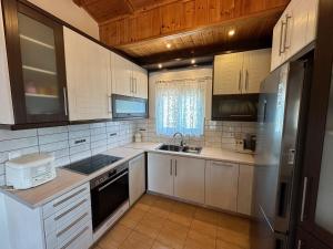 eine Küche mit weißen Geräten und Holzschränken in der Unterkunft Vaso's Paradise in Eretria