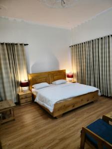 a bedroom with a bed with white sheets and wooden furniture at Laspa Cottage, Bhimtal in Bhīm Tāl