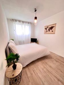 a bedroom with a large white bed and a table at Appartement DisneyLand Paris in Montévrain