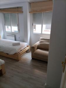 1 dormitorio con 1 cama, 1 sofá y 2 ventanas en Príncipe habitaciones en Madrid